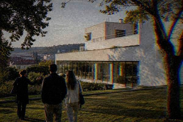 A guide and a couple seen from behind on a garden lawn before a flat-roofed white modernist villa with long bands of glass, Villa Tugendhat