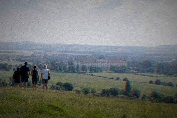 A small group of day visitors standing on a grassy rise looking over wide fields and low rolling hills under a big sky, Slavkov and Austerlitz