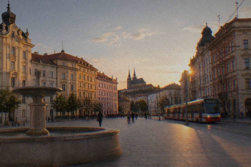 A tram moving along a street lined with older buildings in the evening