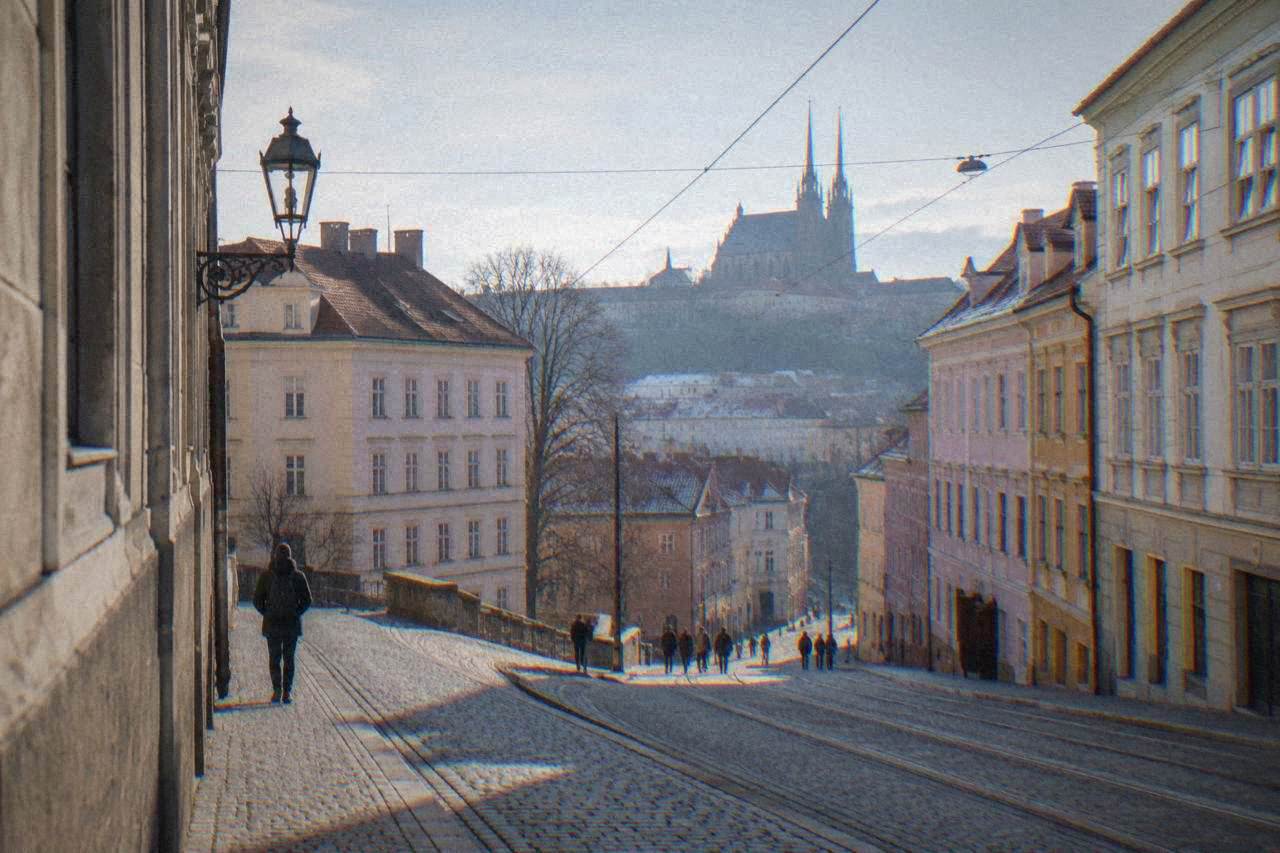 Twin-spired cathedral towers rising above rooftops on a hill in Brno