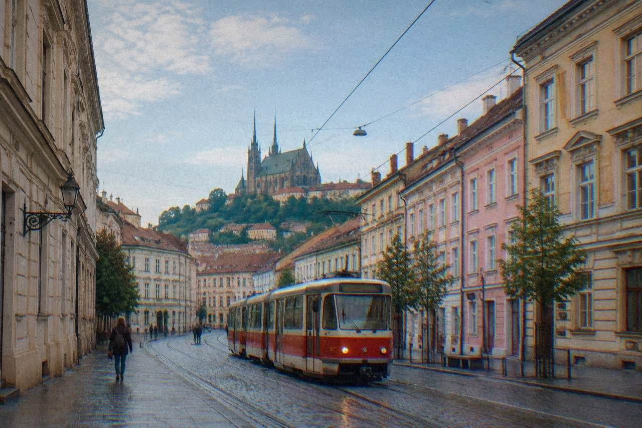 A red and white tram moving along a street in central Brno past period buildings