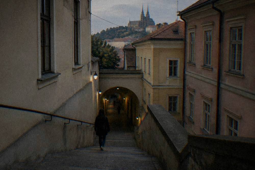 Narrow stone stairway descending from a Brno church into a dim underground corridor