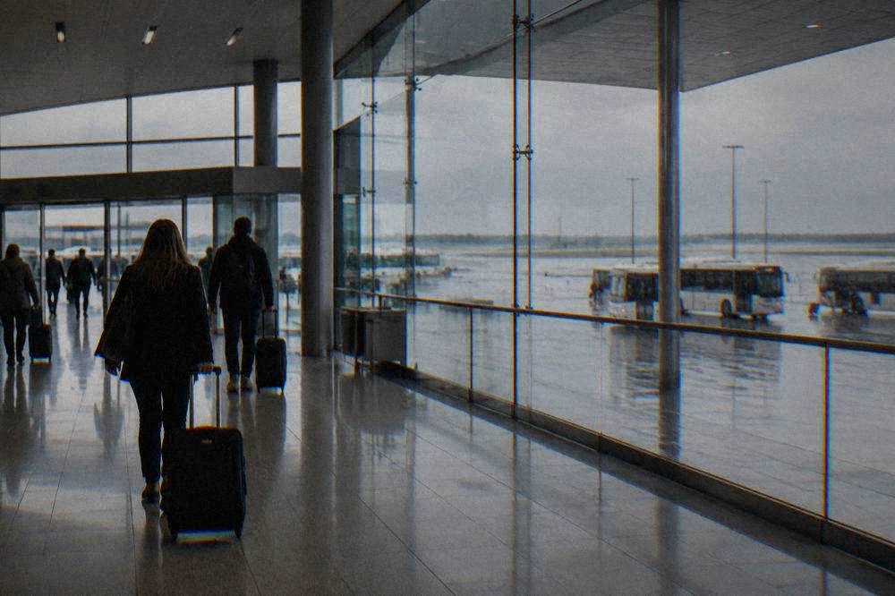 Travellers with suitcases walking through a modern airport arrivals hall