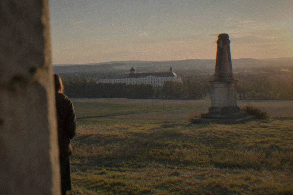 A stone memorial standing on open grassland near Slavkov u Brna