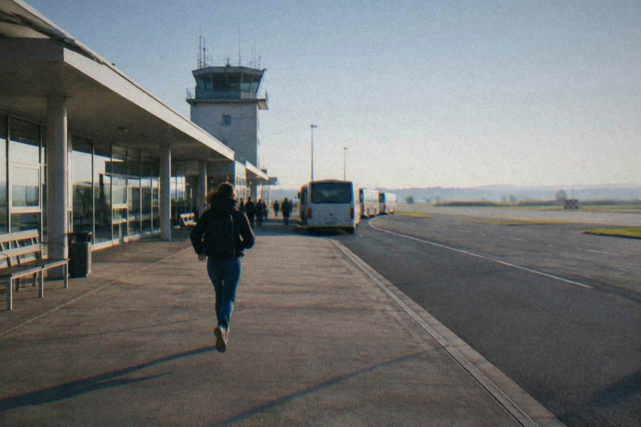 A small regional airport terminal building with a low control tower under a clear sky