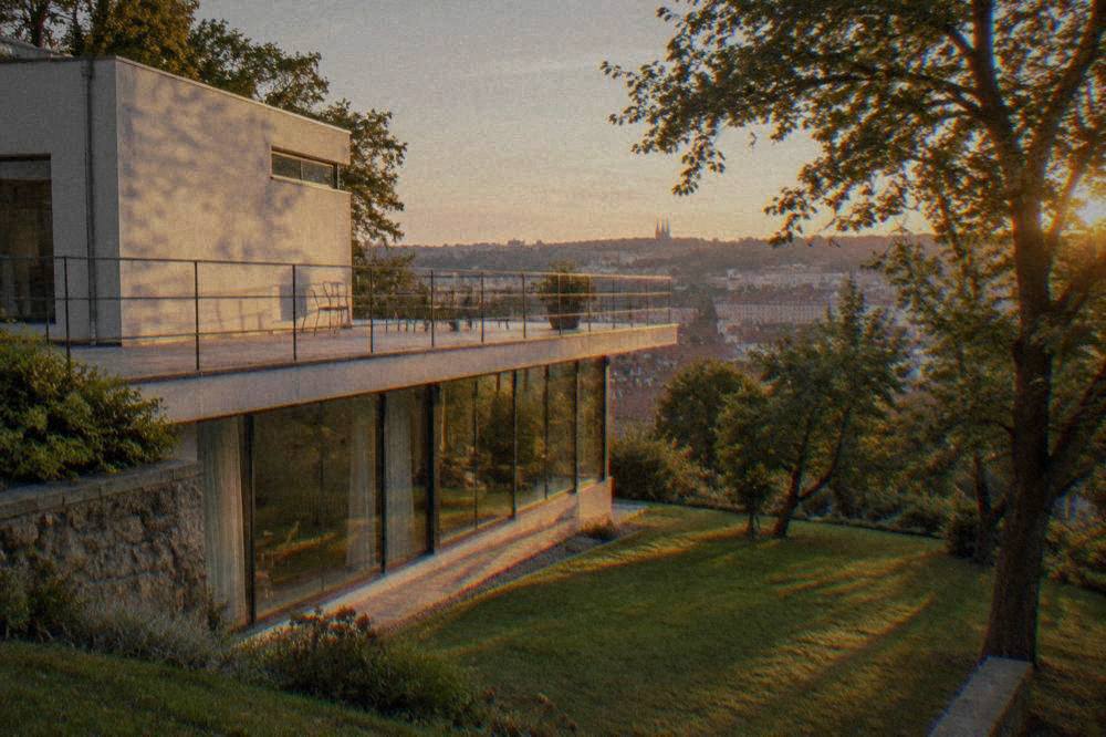 A modernist villa exterior with a terrace overlooking a garden, in the style of Brno's late-1920s architecture