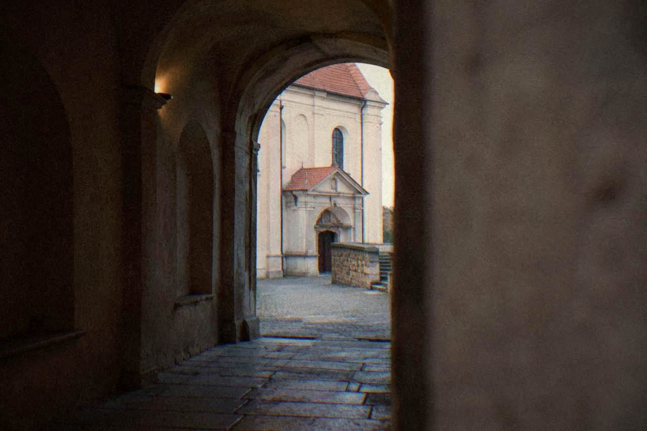 Dim stone corridor beneath a church with arched recesses carved into the walls