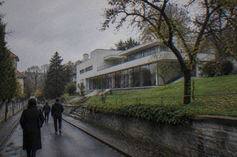 Visitors walking down a residential street toward a villa entrance in a leafy Brno neighbourhood