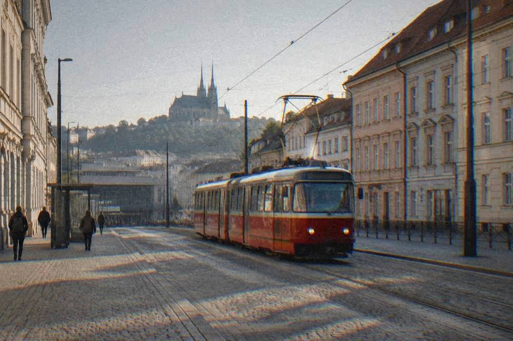 A red Brno tram departing the stop outside the main train station