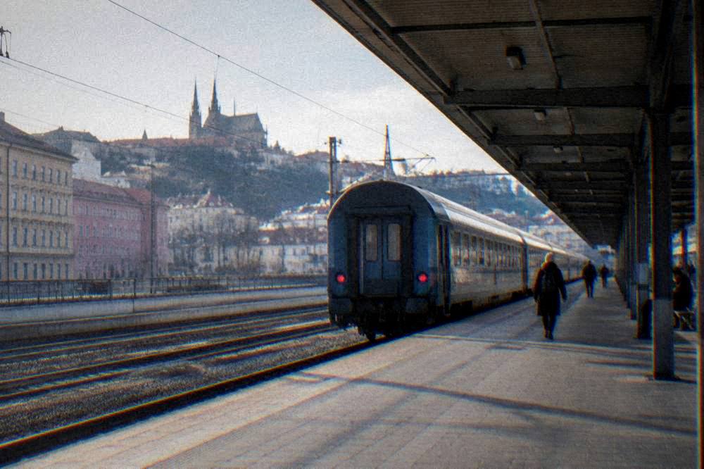 A long-distance train waiting at a platform under the station roof in Brno
