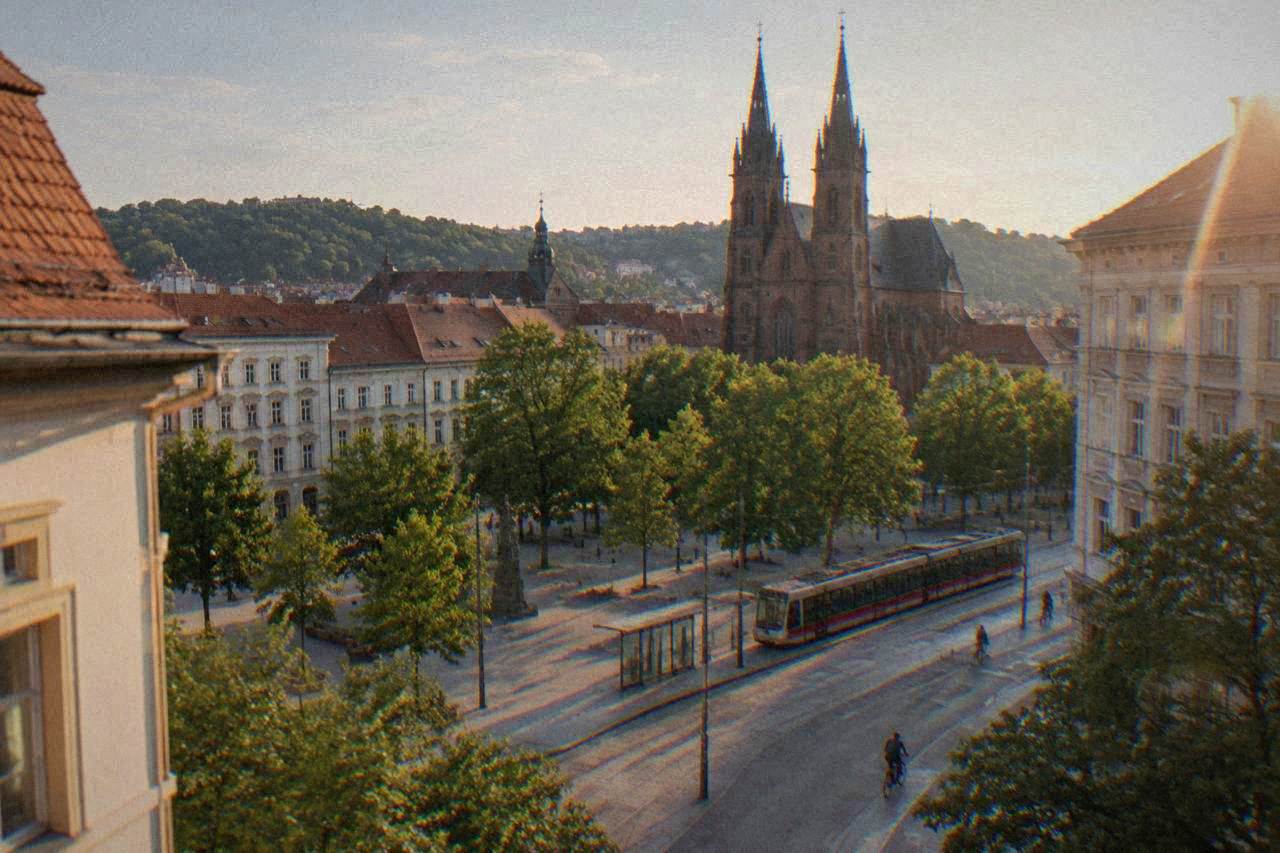 Twin Gothic towers of a brick basilica rising above a leafy square in a city quarter