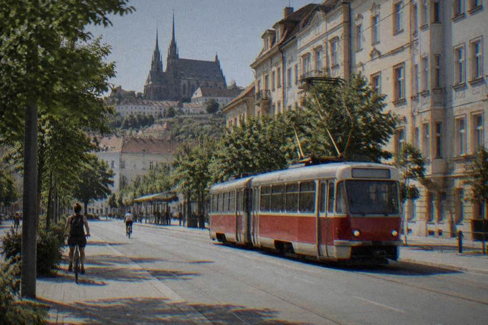 A red tram passing older apartment buildings on a street in a Czech city