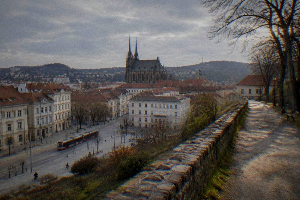 Sunlit path on a castle hill with city rooftops spreading below