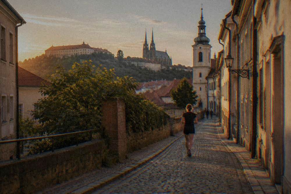 Narrow cobbled street climbing between old buildings toward a church tower