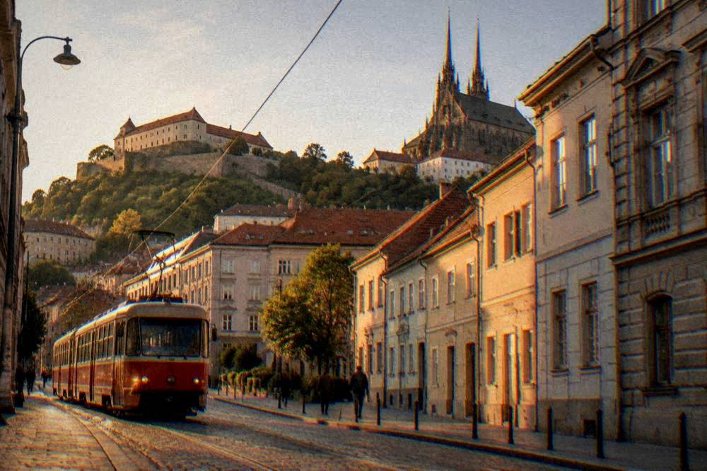 Red tram moving along a street with old facades in a European city