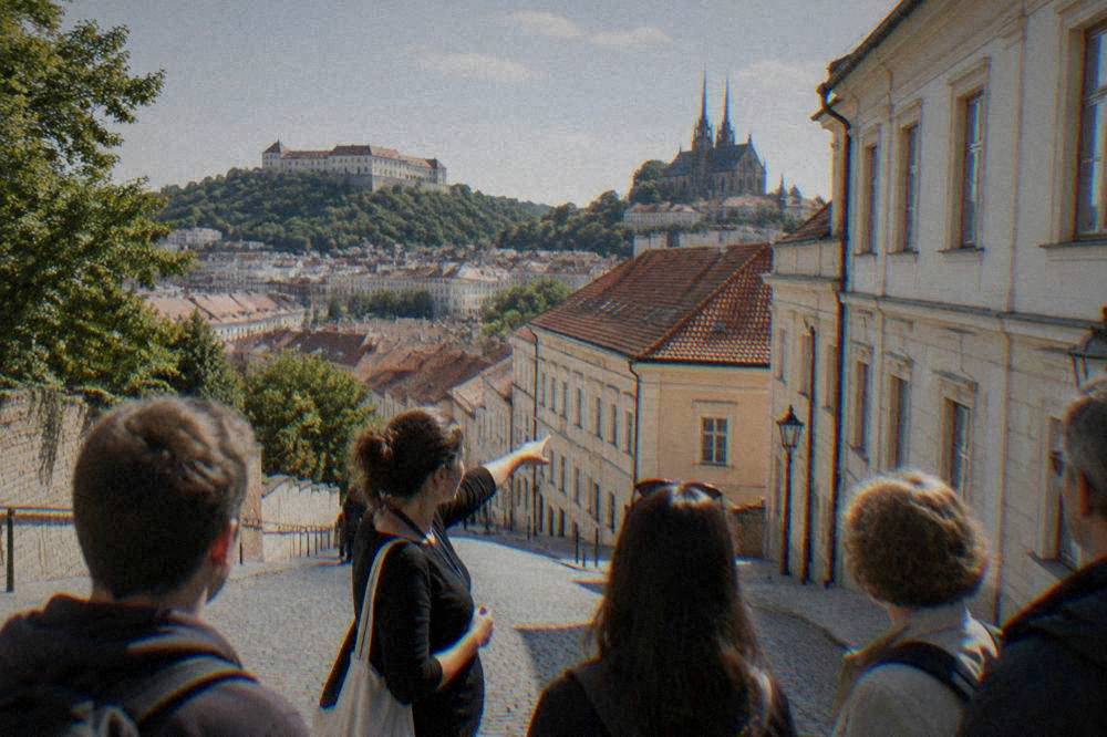 Guide pointing at building facades while a small group listens on a city street