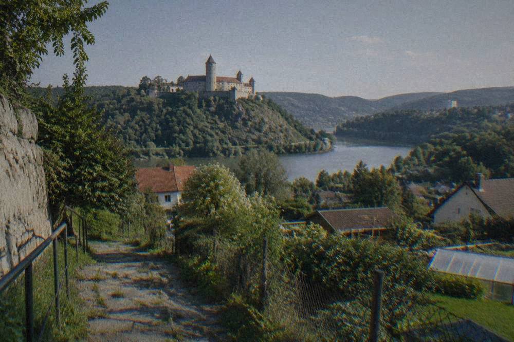 A stone castle with towers standing above a river bend and forest