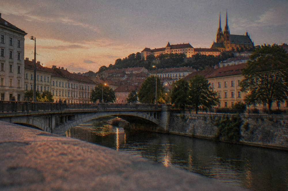 Evening view of an illuminated castle on a hill above city rooftops in Brno