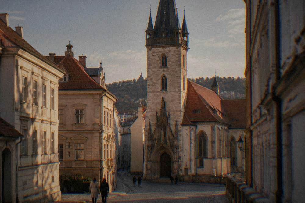 An old town hall tower rising above a street with a gothic portal below it
