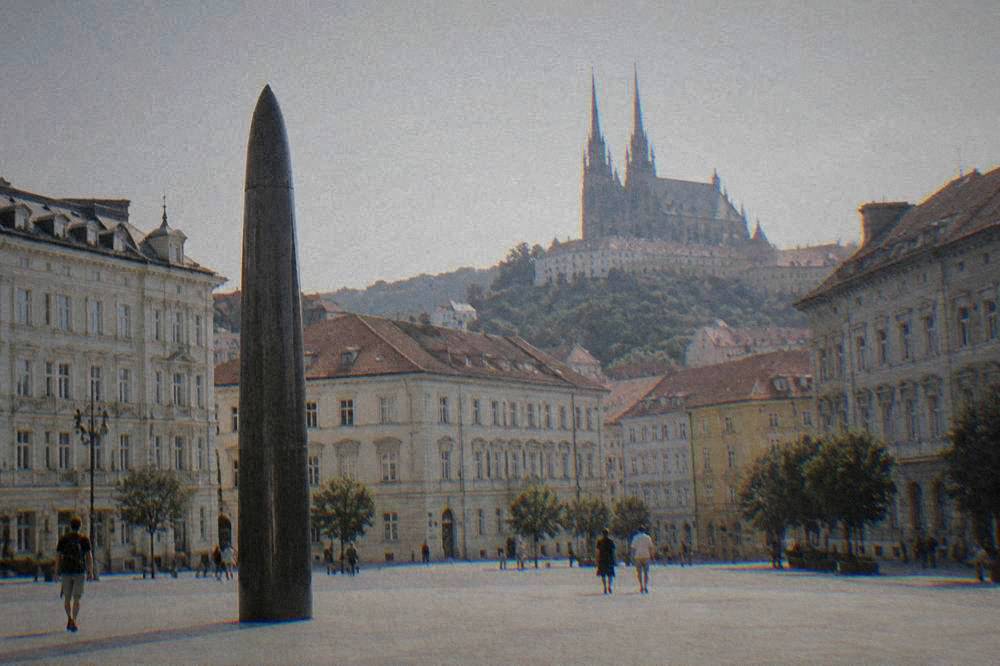 Twin gothic spires of a cathedral rising over rooftops on a hill above a city