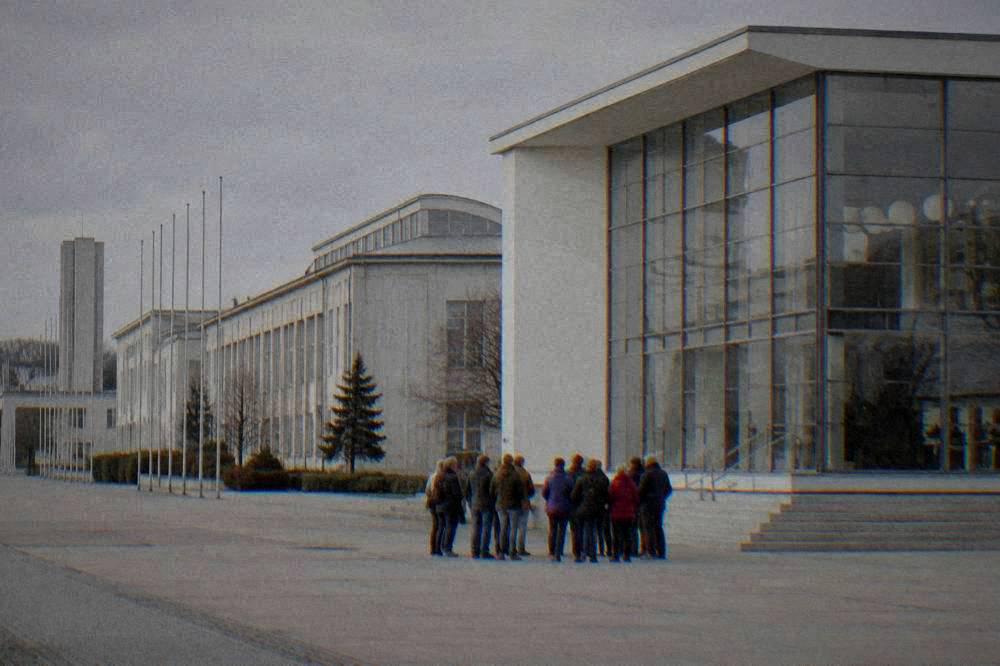 Tour group outside a white modernist villa with a large glazed wall