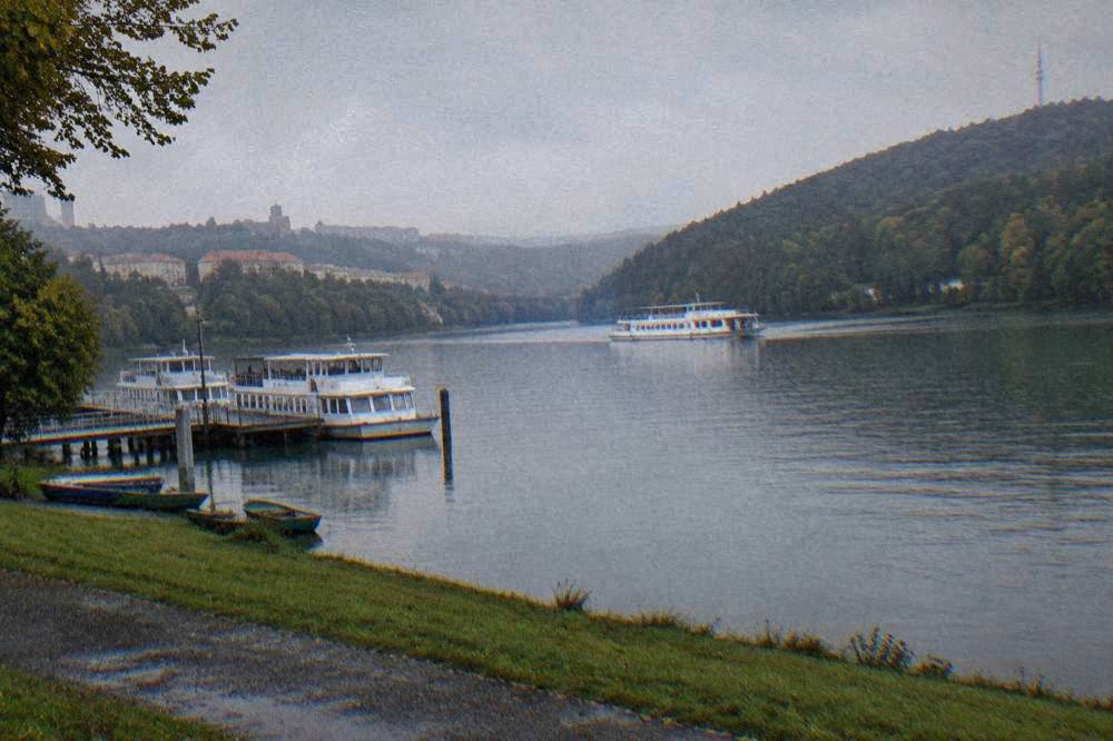 A white passenger ferry crossing a calm lake with forested banks on both sides