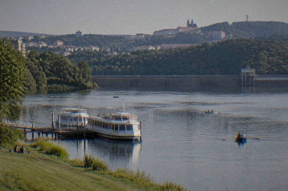 A wide dam wall with a roadway across the top holding back a lake at dusk