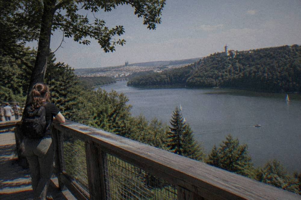 A wooden viewing platform overlooking a wide reservoir with forested banks and small boats