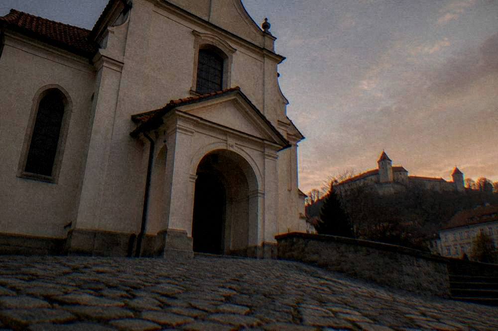 Fortress walls and towers of a hilltop castle above a city at dusk