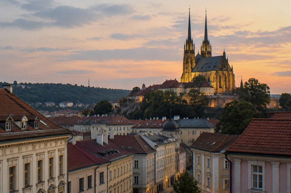 The twin cathedral towers illuminated against an evening sky above Brno