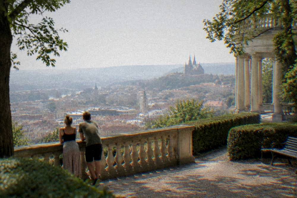 Couple resting at a stone balustrade above a wide city panorama