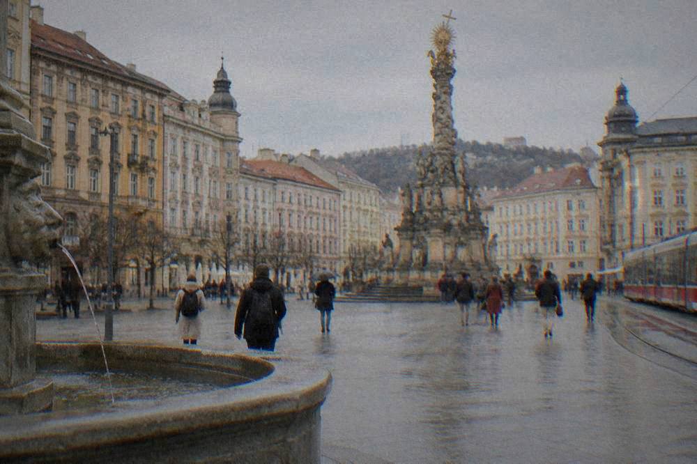 The baroque plague column rising among people crossing a wide city square