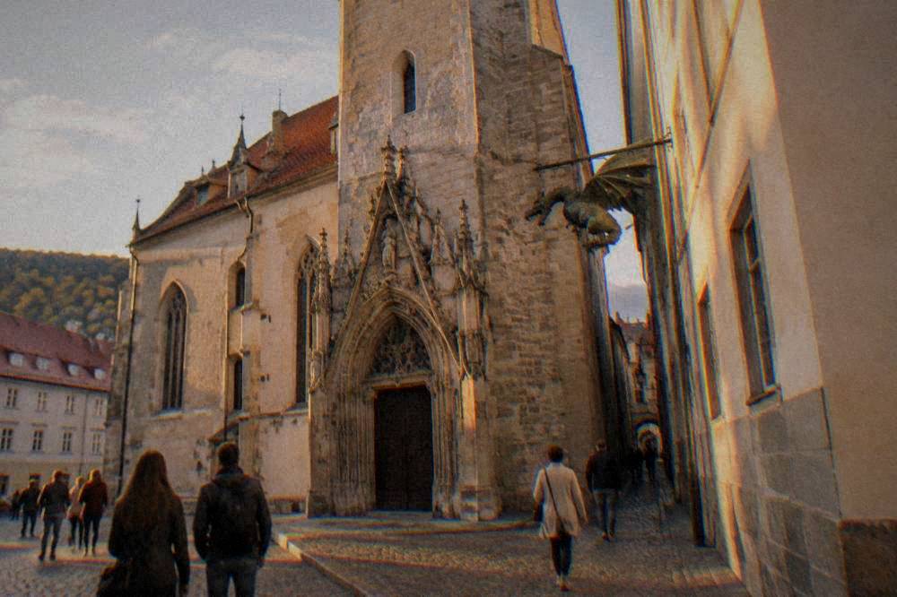 Visitors walking past the entrance of an old town hall with a dragon figure hanging in a passage