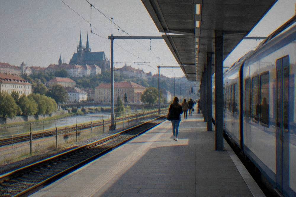 A train waiting at a platform under a modern station roof in Brno