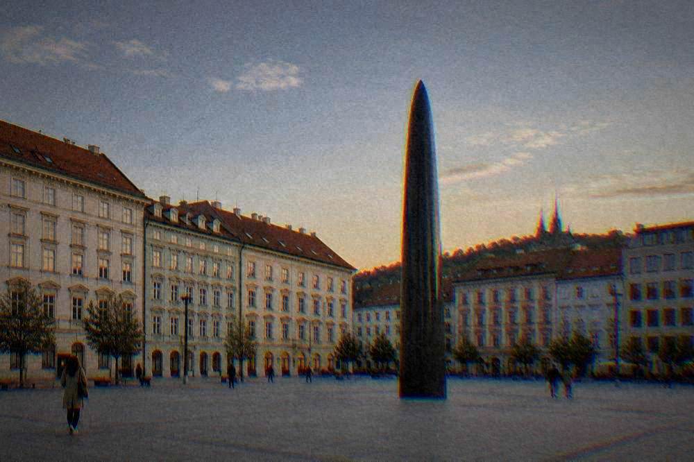 Wide pedestrian square with colourful facades and an astronomical clock at dusk