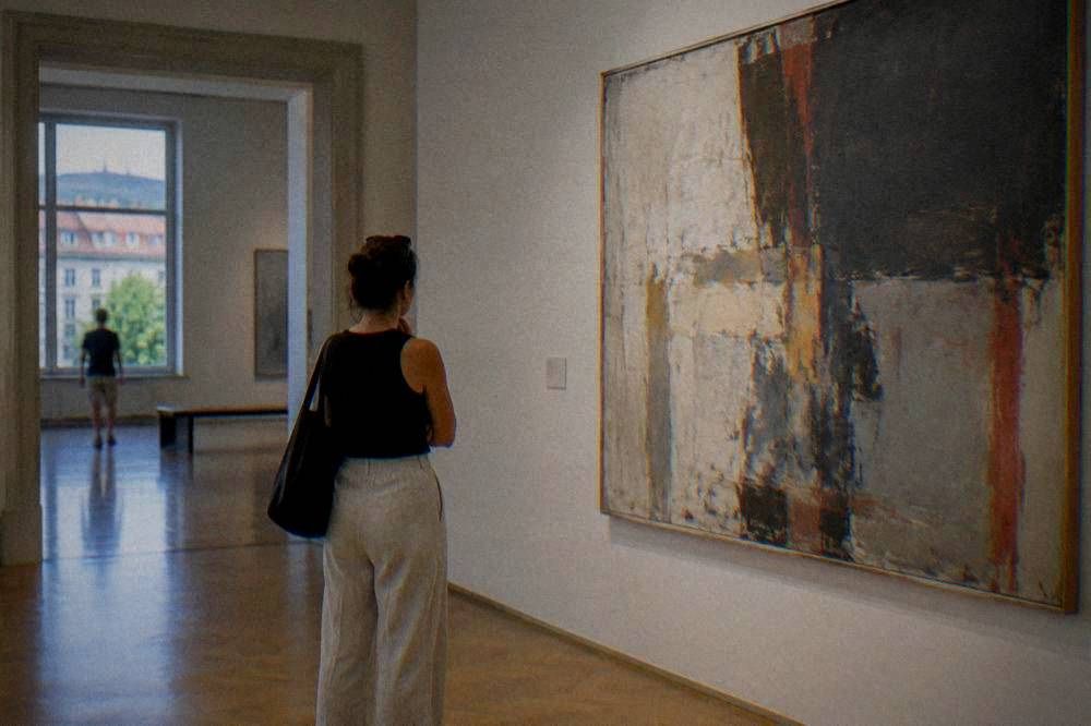 Visitor reading a wall label beside a large abstract painting