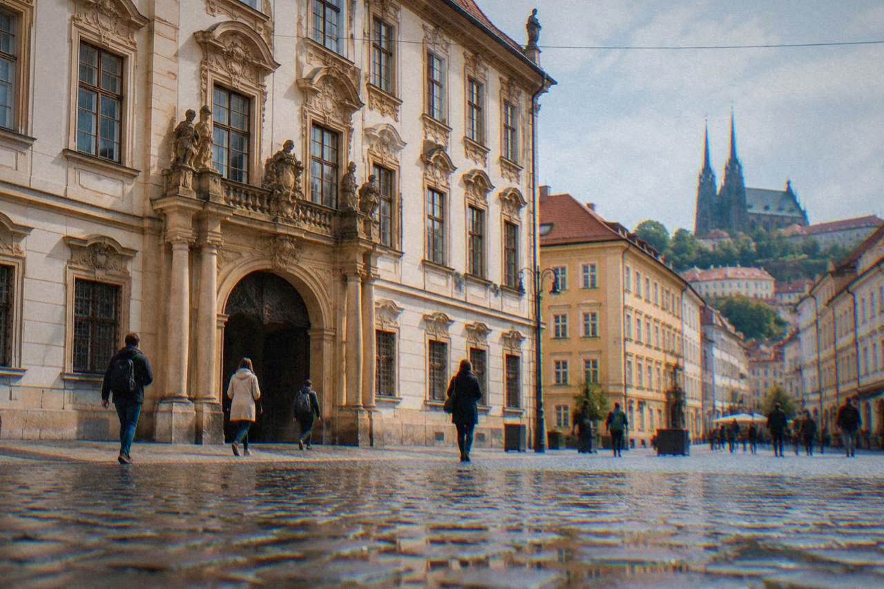 A baroque palace facade on a Brno square with visitors walking past its arched entrance