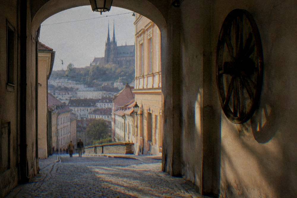 A large wooden cart wheel hanging on a wall inside a historic passage in Brno
