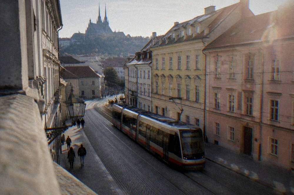 Modern tram passing colourful buildings on a Brno street