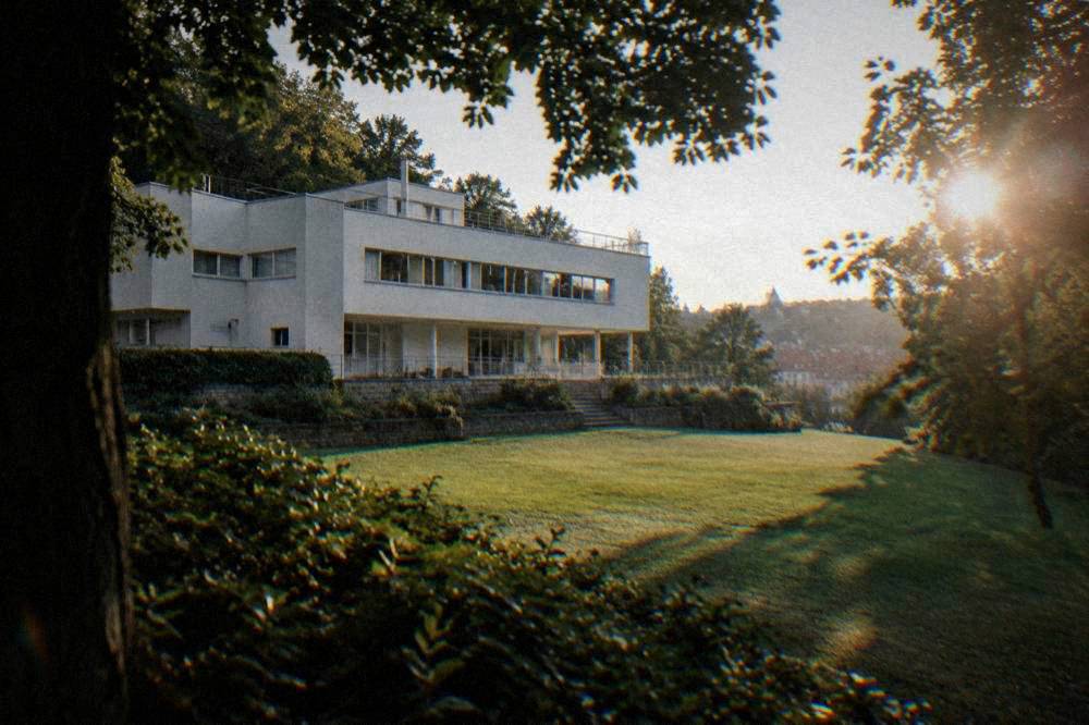 A modernist white villa with horizontal windows seen across a lawn