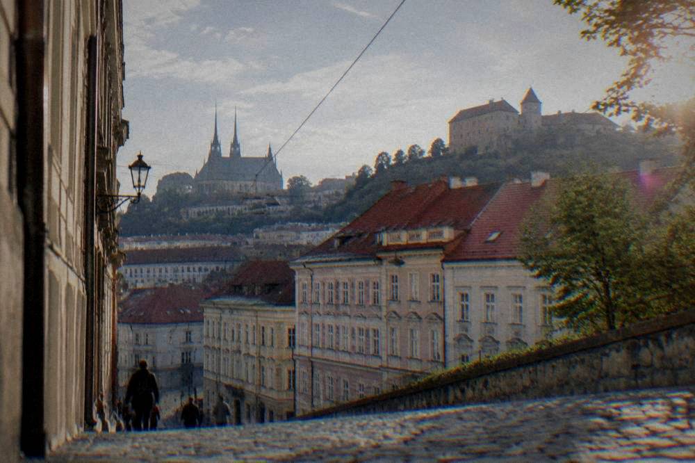 A stone castle on a hill above red rooftops in Brno