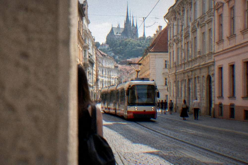 A tram moving along a street lined with historic buildings in Brno