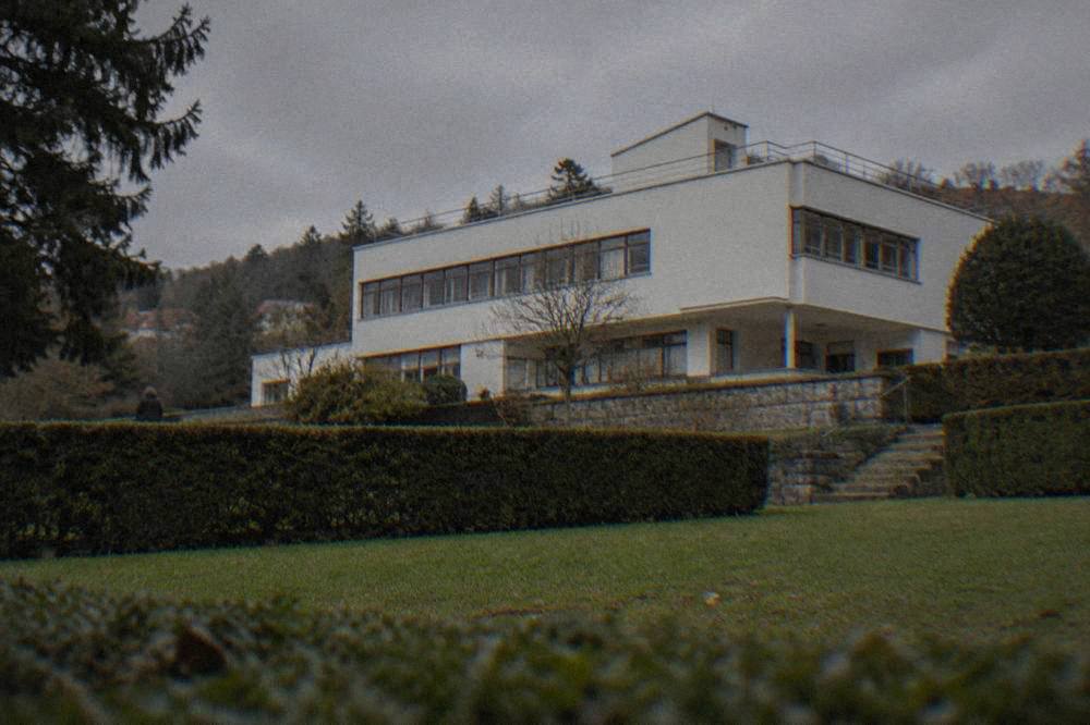 A garden with trimmed hedges in front of a light modernist villa in daylight