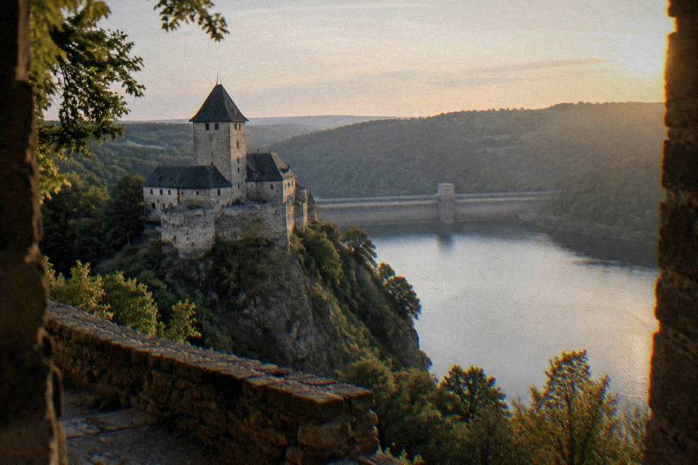 A long concrete dam wall holding back a wide reservoir between wooded hills