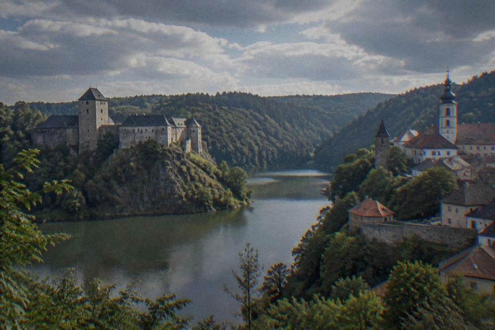A town on a hillside above a river with old towers and rooftops