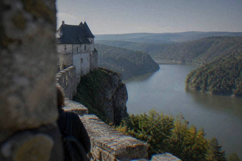 A view across a wide valley from a castle rampart toward hills fading into distance