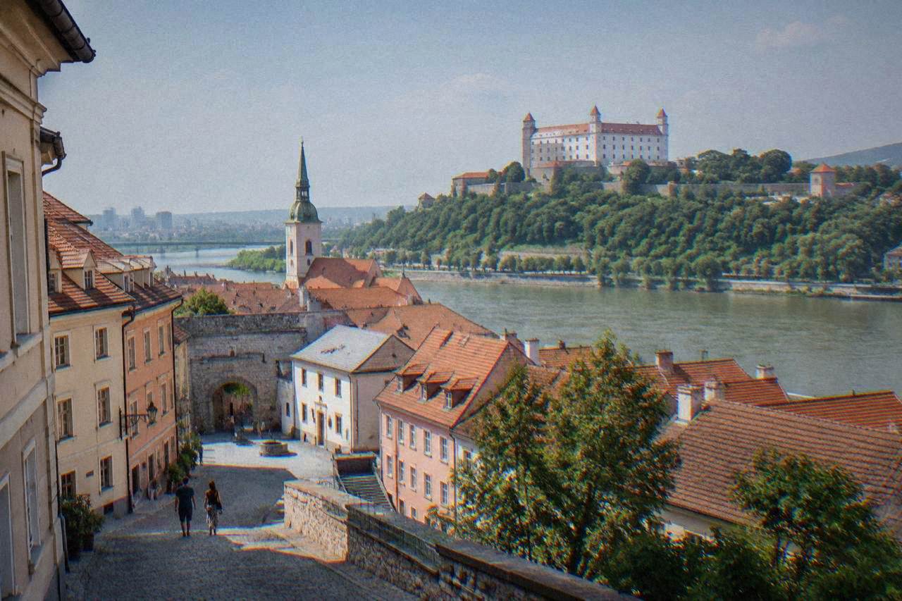 Castle hill above a river with an old town rooftop skyline in the foreground