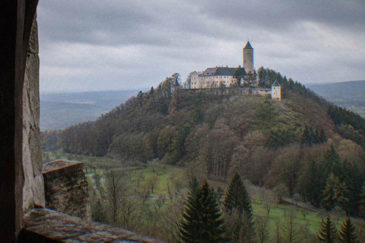A stone castle on a forested hill above rolling countryside in South Moravia
