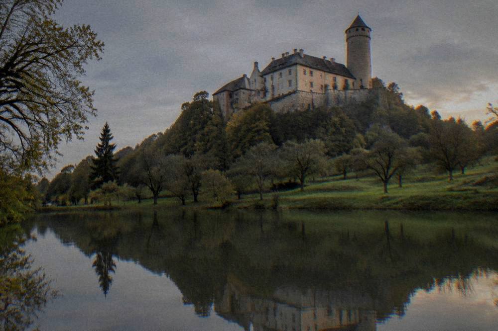 A UNESCO-listed castle reflected in a pond at golden hour