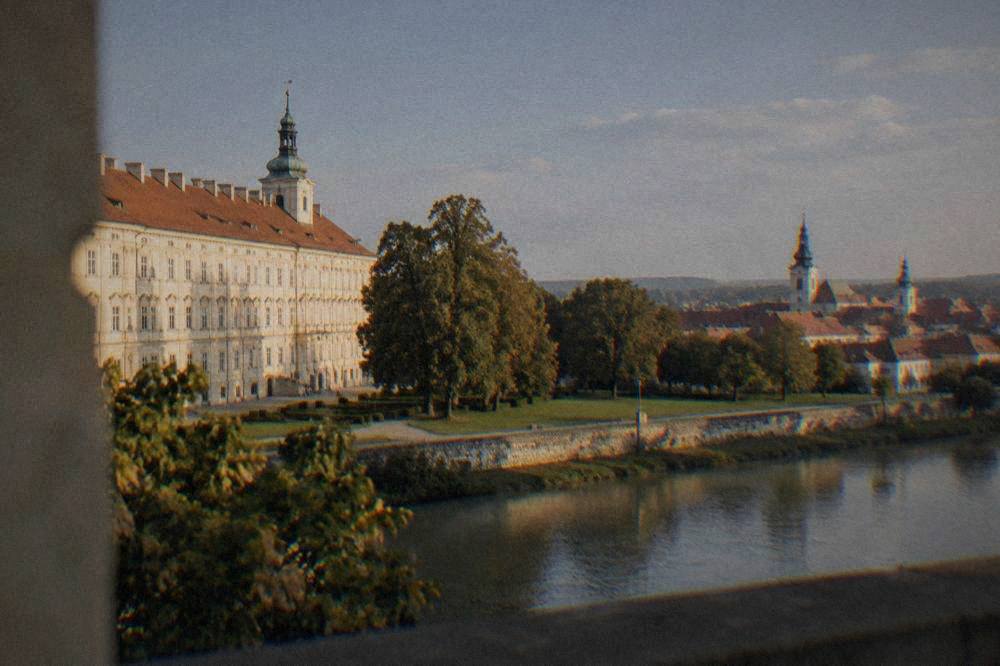 View across a river town with church towers and red rooftops under a blue sky